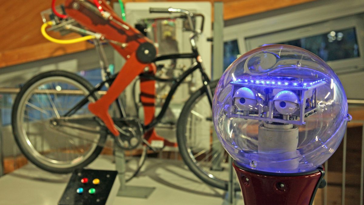 Dieses Bild zeigt den Kopf eines Roboters und Roboterbeine auf einem Fahrrad bei der langen Nacht der Museen.