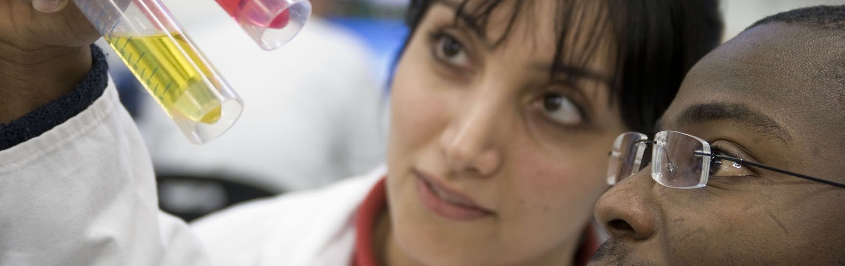 Zwei Personen im Labor schauen auf zwei Röhrchen mit verschiedenfarbiger Flüssigkeit