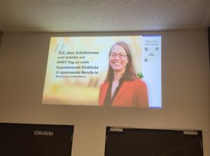 Ein weiteres projiziertes Zitat von Dr. Claudia Schilling, die die vielen spannenden Einblicke für Schüler auf dem MINT-Tag lobt. Ein QR-Code für mehr Informationen ist ebenfalls zu sehen.